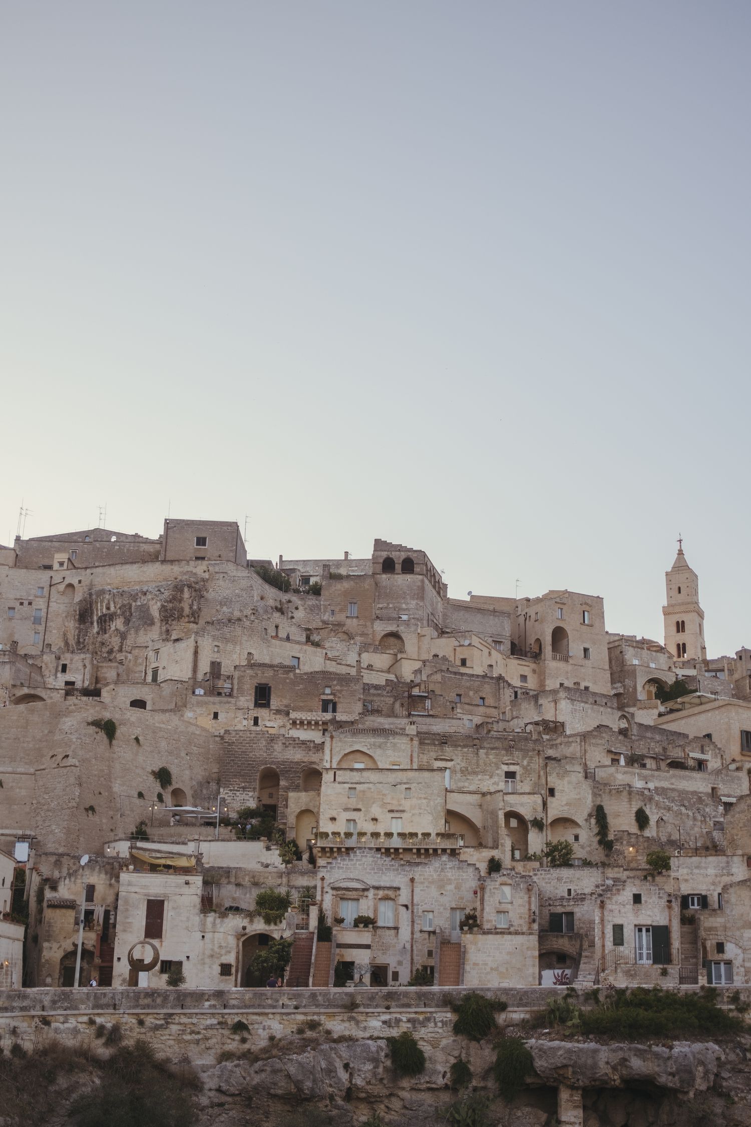 Ancient hillside town with white stone buildings cascading down the slope at sunset.