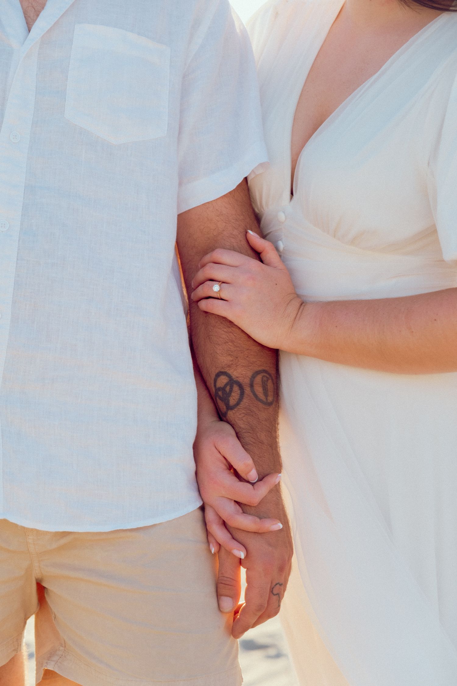 Close-up detail of hands holding each other against white clothing.