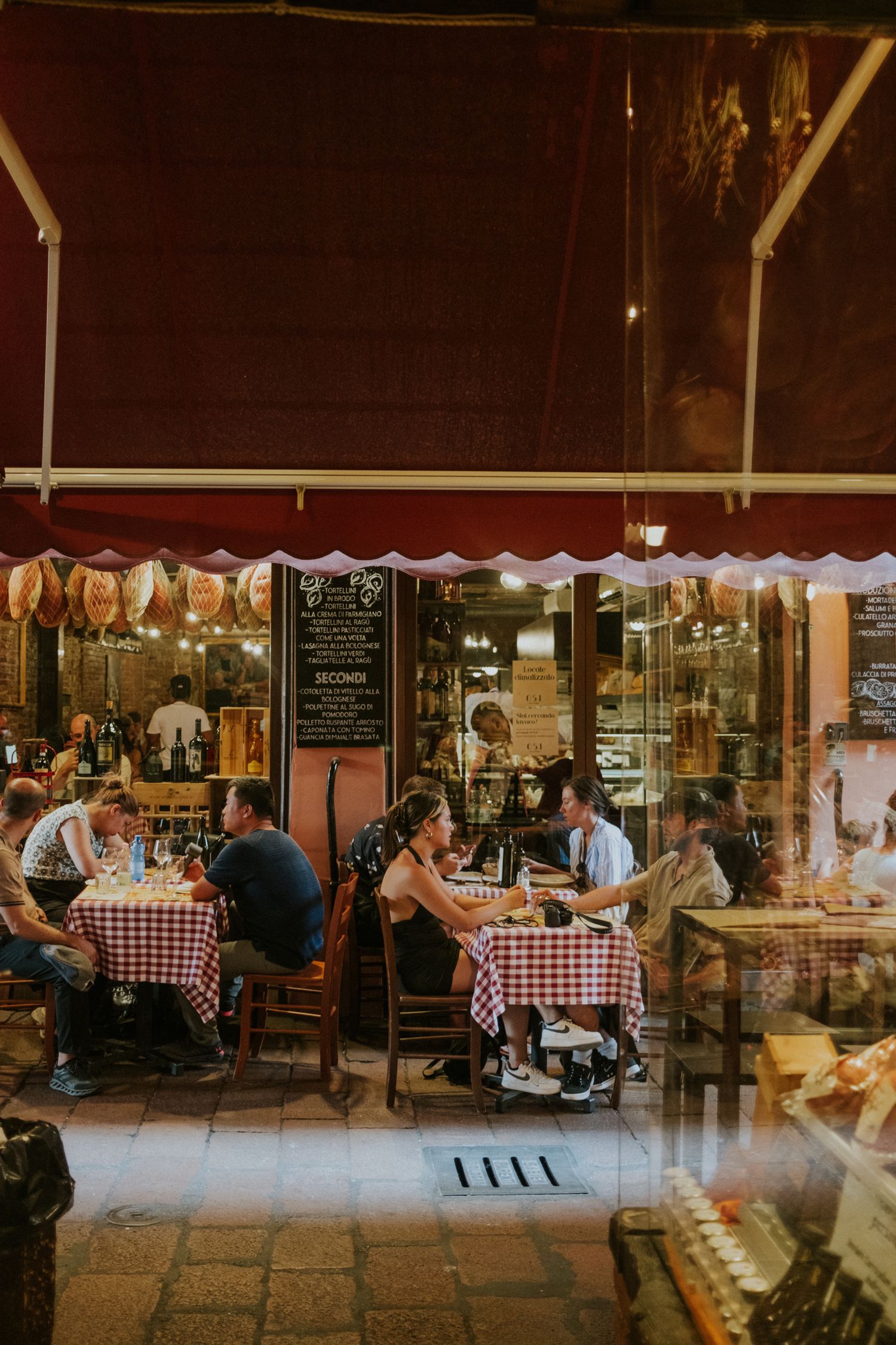 Cozy outdoor cafe with checkered tablecloths and customers dining under awnings at dusk.