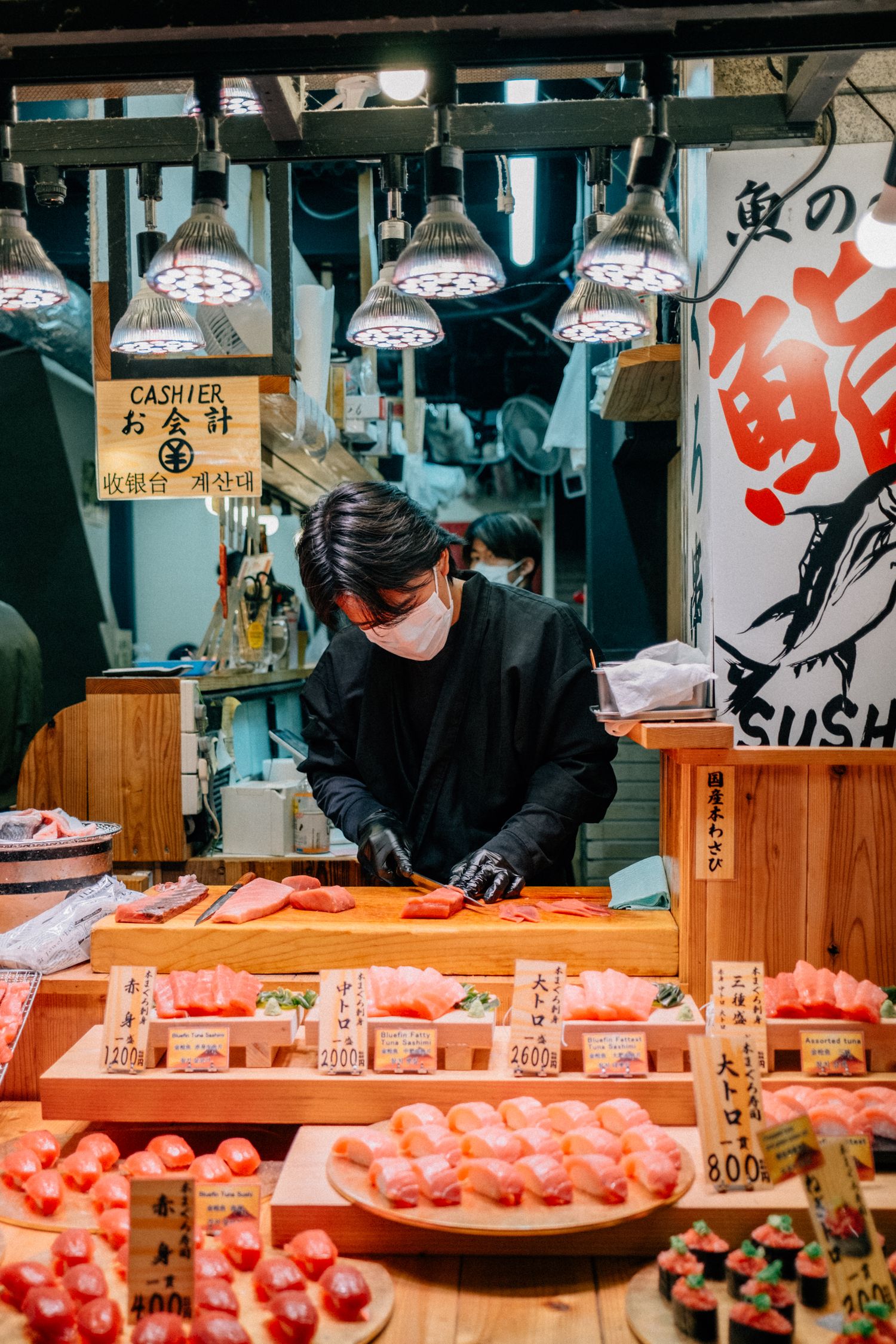 Fresh sushi and seafood display at a Japanese market counter with traditional signage.