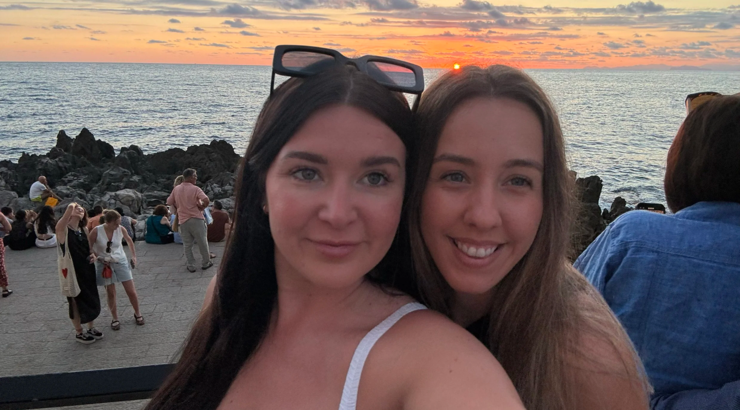 Friends watching a vibrant ocean sunset together on the beach.