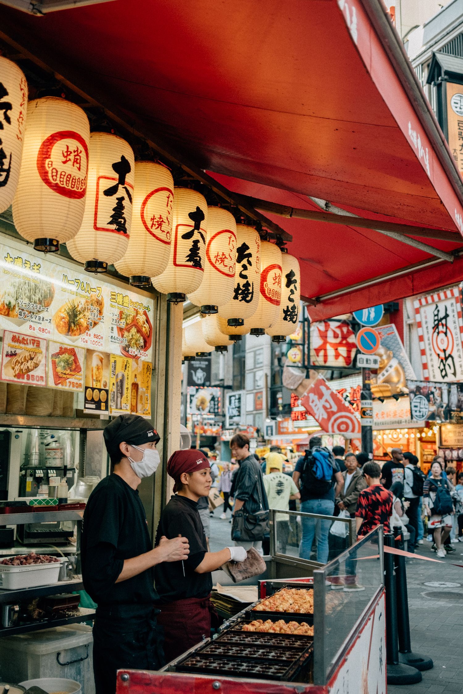 Street vendors preparing and selling takoyaki at a traditional Japanese food market.