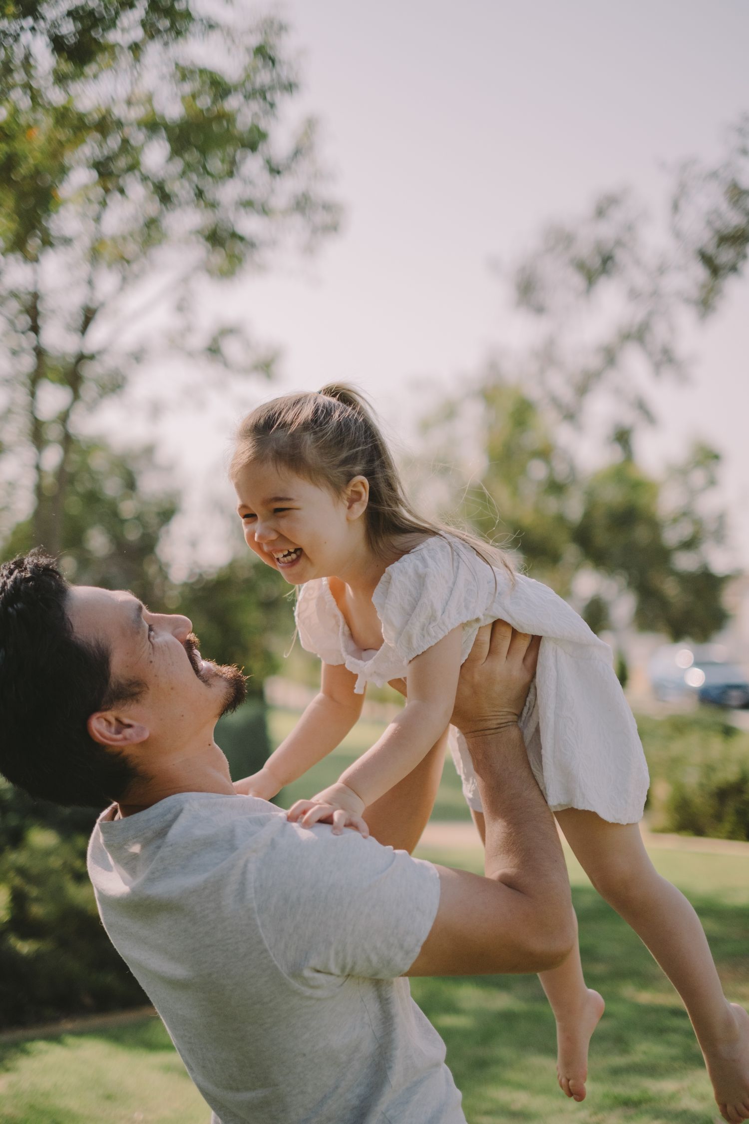 A playful outdoor photoshoot showing joyful interaction in a sunny park setting.