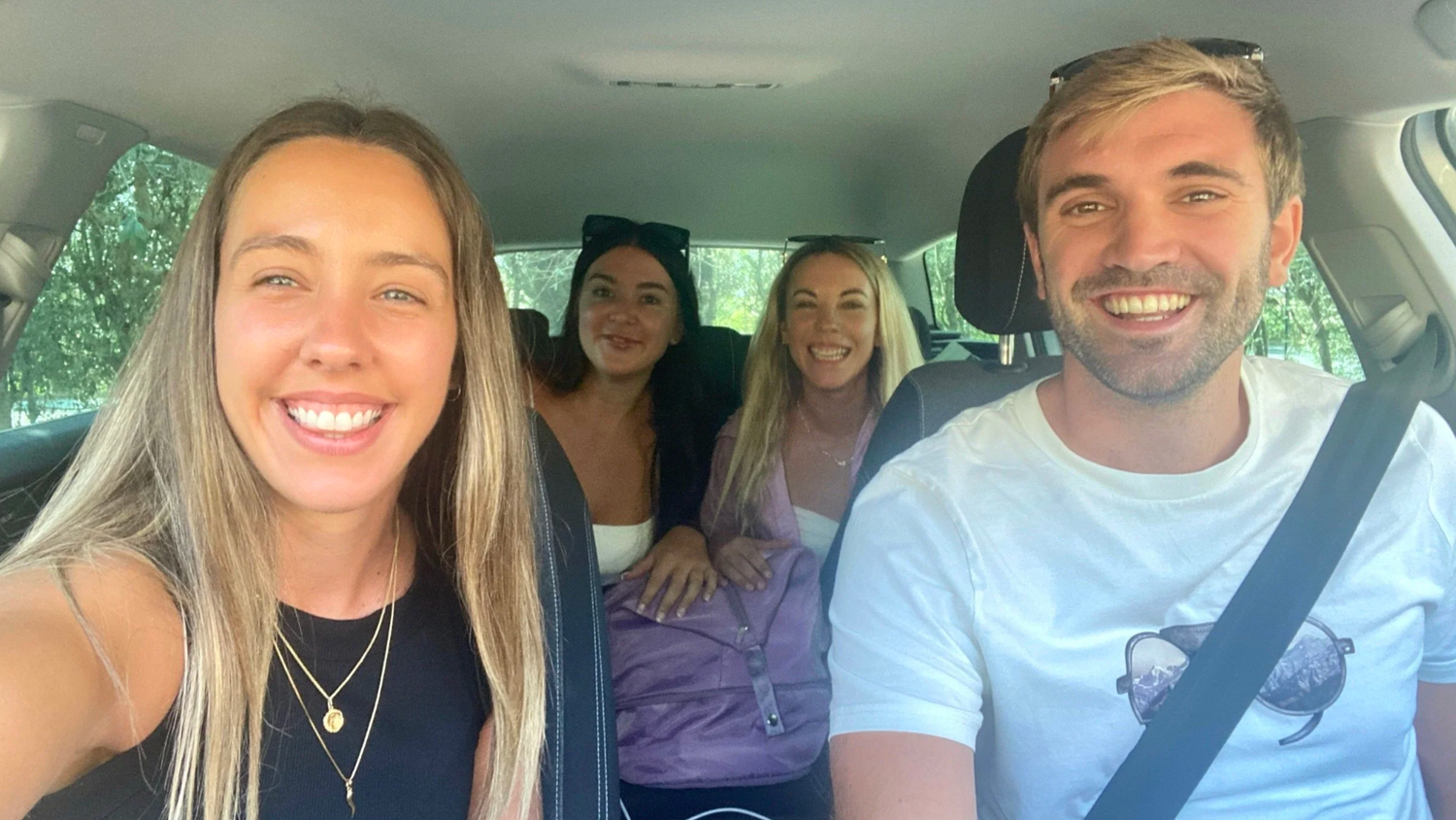 Friends sharing laughs while riding together in a car on a sunny day.