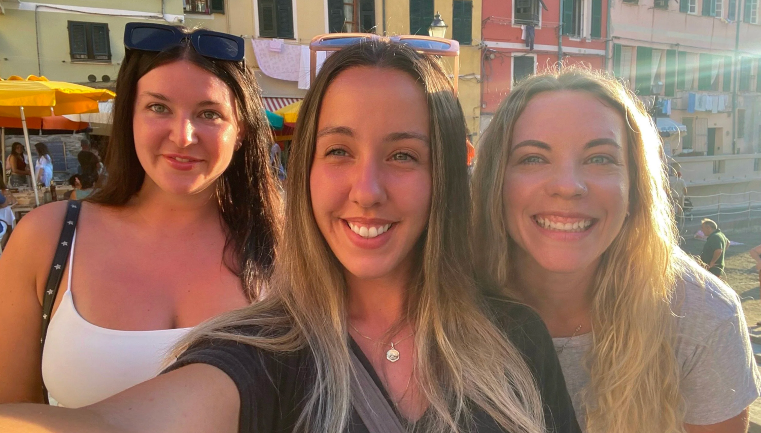 Friends posing together for photos along a colorful Italian coastal town.