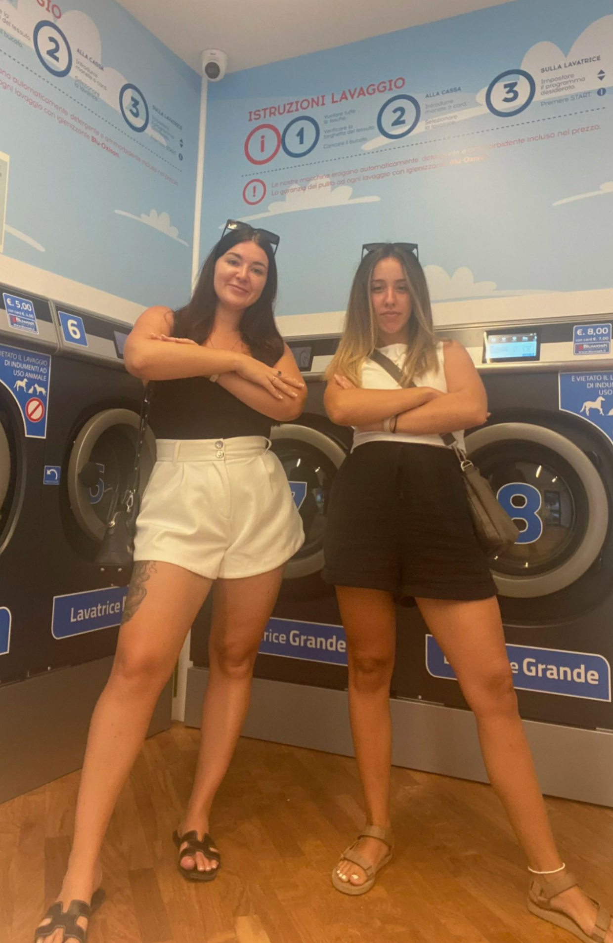 People posing playfully in front of washing machines at a laundromat.