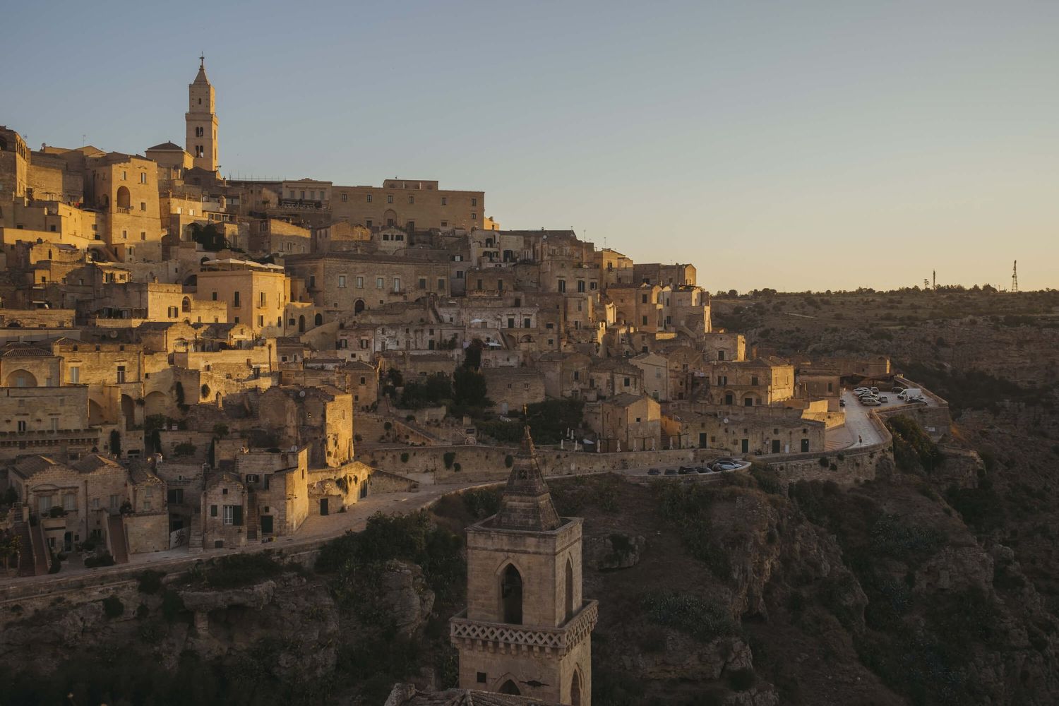 Ancient stone buildings and structures of Matera, Italy at sunset with warm golden light illuminating the historic city.