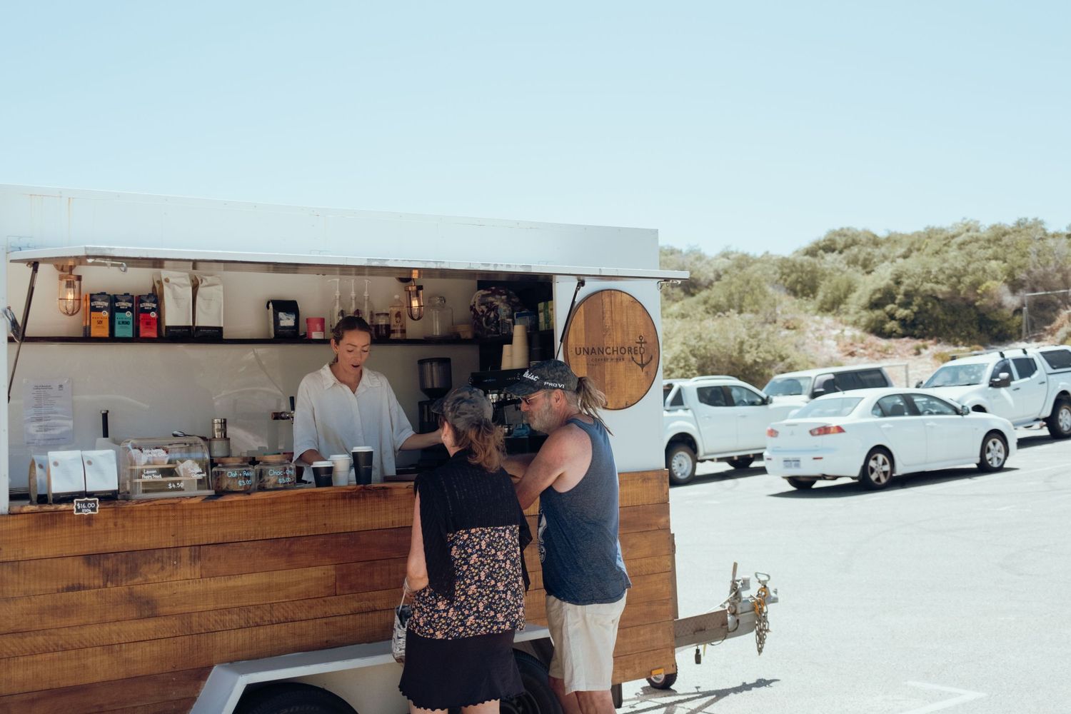 Outdoor coffee shop with wooden exterior and parked cars visible in the background.