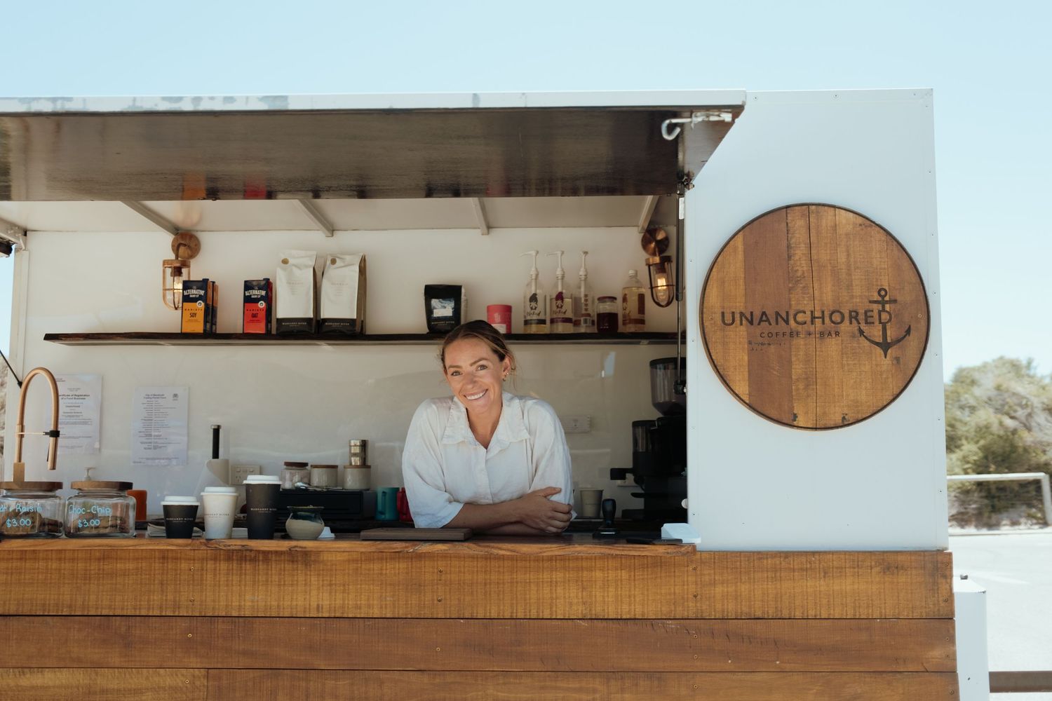 Clean minimalist bar counter with wooden accents and shelving displaying bottles.