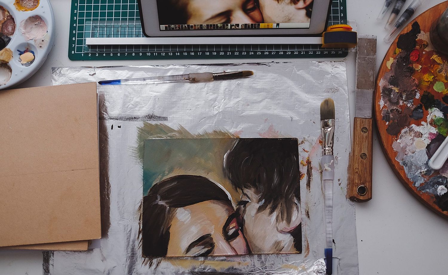Workspace with cutting mat, art supplies and craft materials spread across a desk.