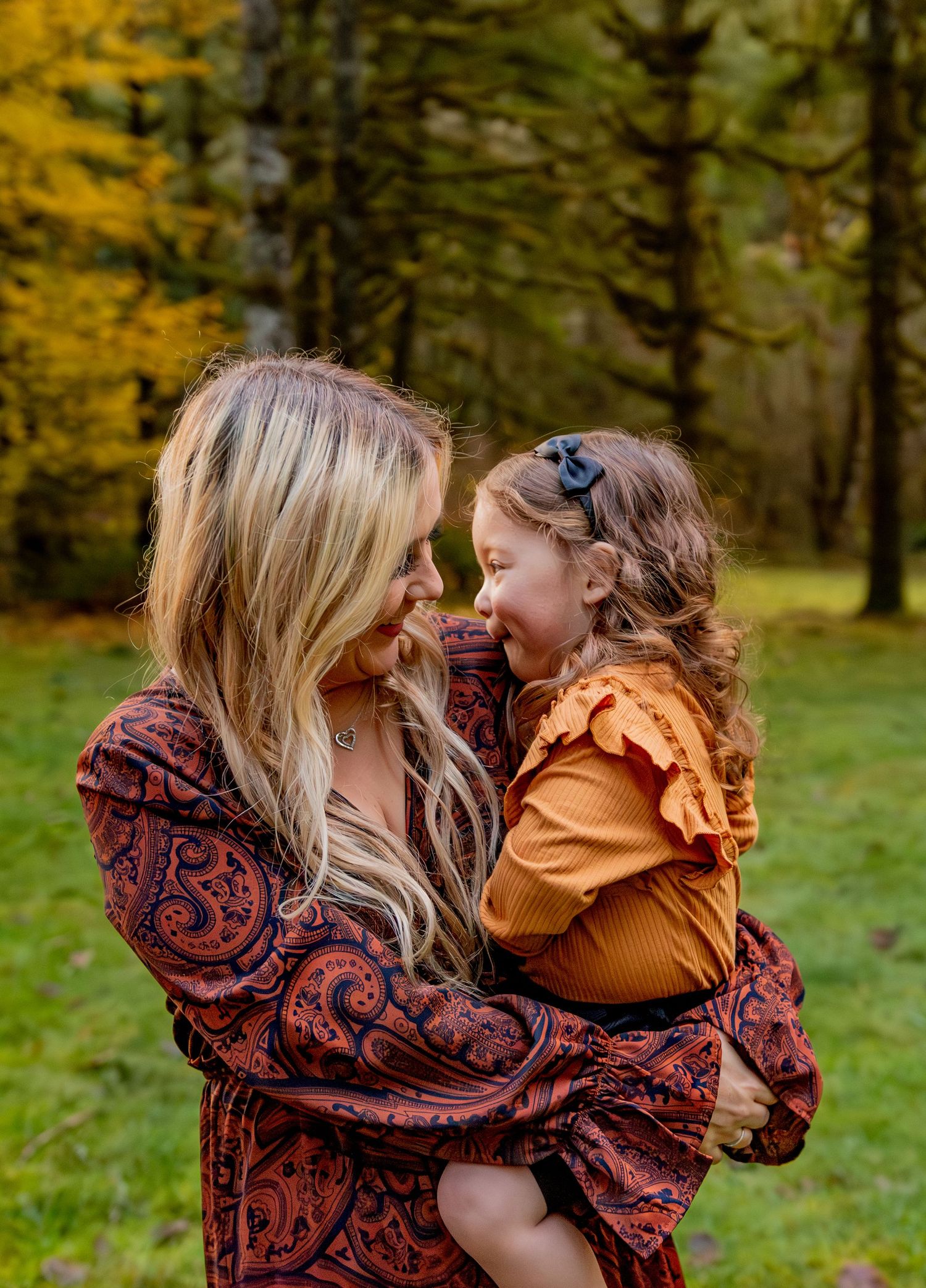 A parent and child share tender moments outdoors in autumn, wearing burgundy and mustard colored outfits. Silver Falls State Park, OR