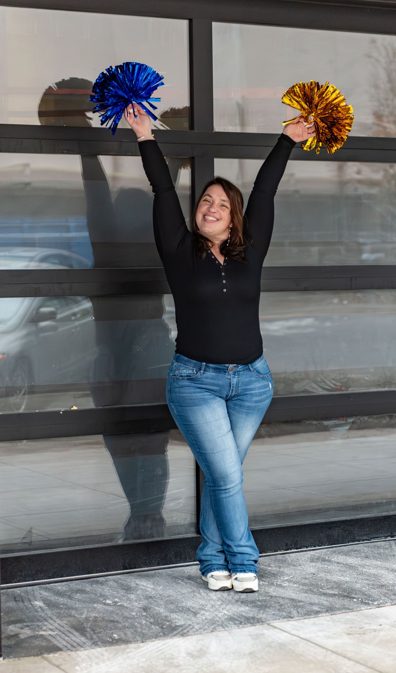 Headshot of woman with pompoms blue and gold with red brick background, for branding images, located in Salem, OR.