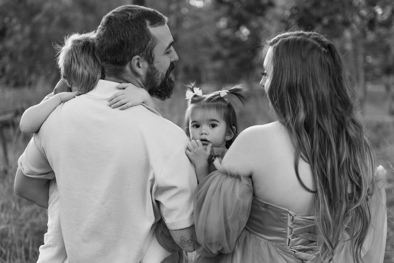 Black and white photo of a family of four outdoors sharing an intimate moment together. Salem, OR