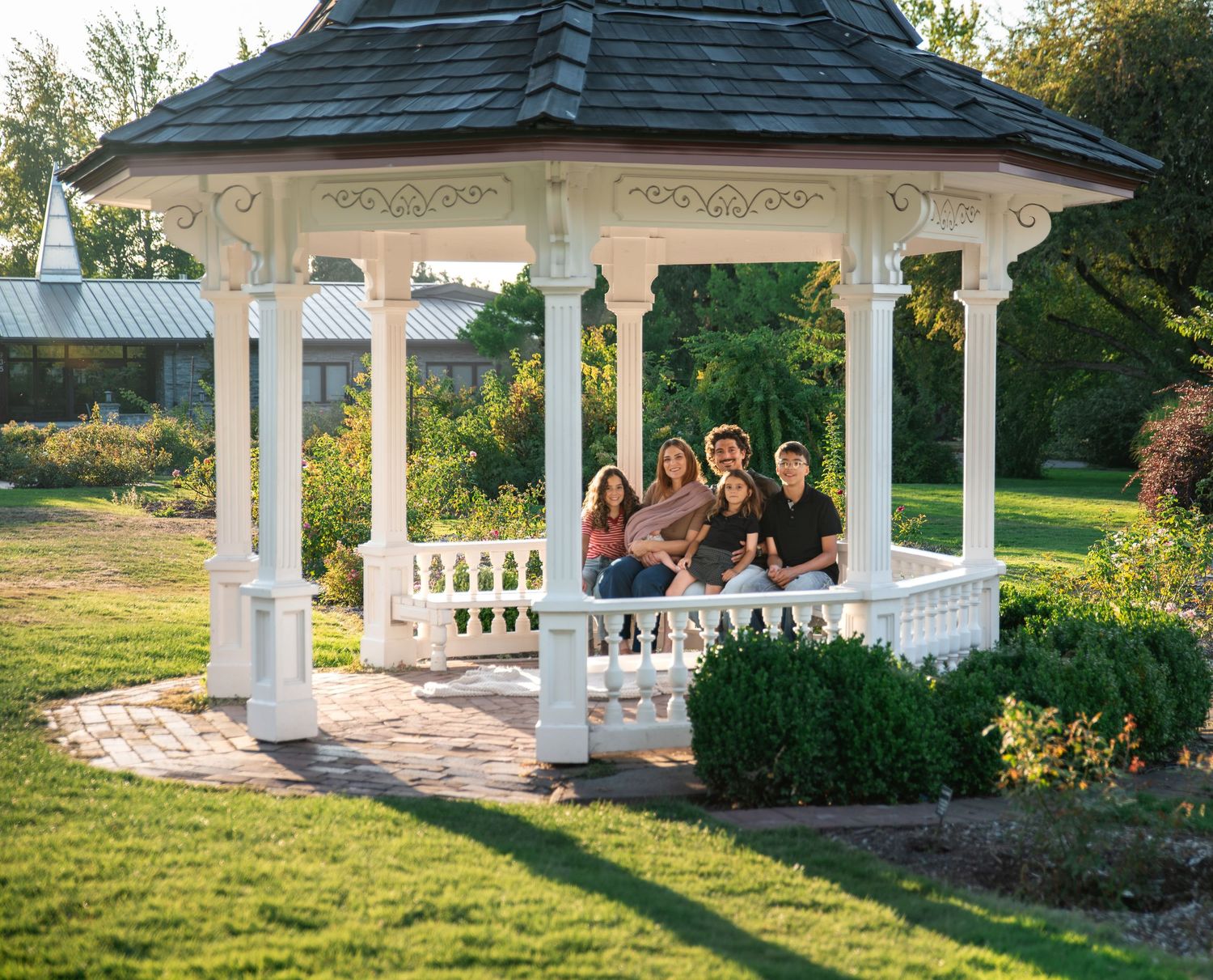 Family gathered under a gazebo on a sunny day for a family portrait photo in Salem, OR.