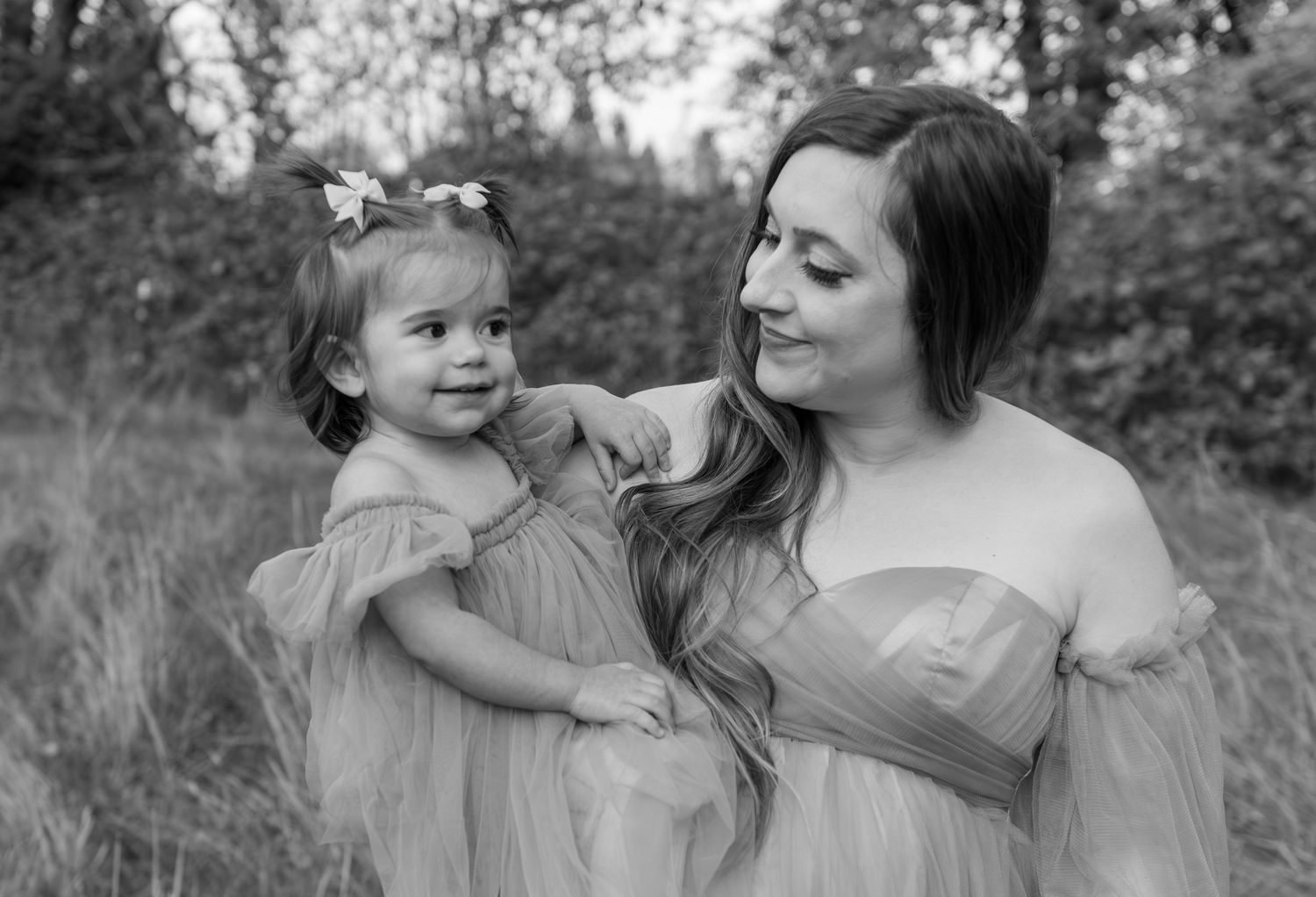 Mother and toddler daughter posing in a field with fall foliage in Salem, OR