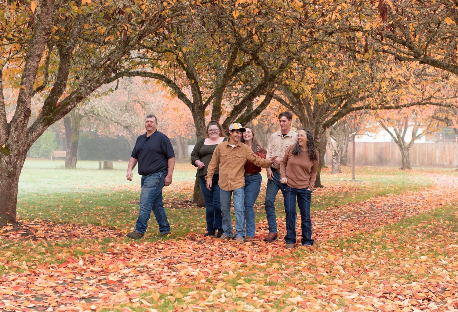 Group of people enjoying an autumn day in a park with fallen orange and yellow leaves scattered on the ground. Location Stayton, OR