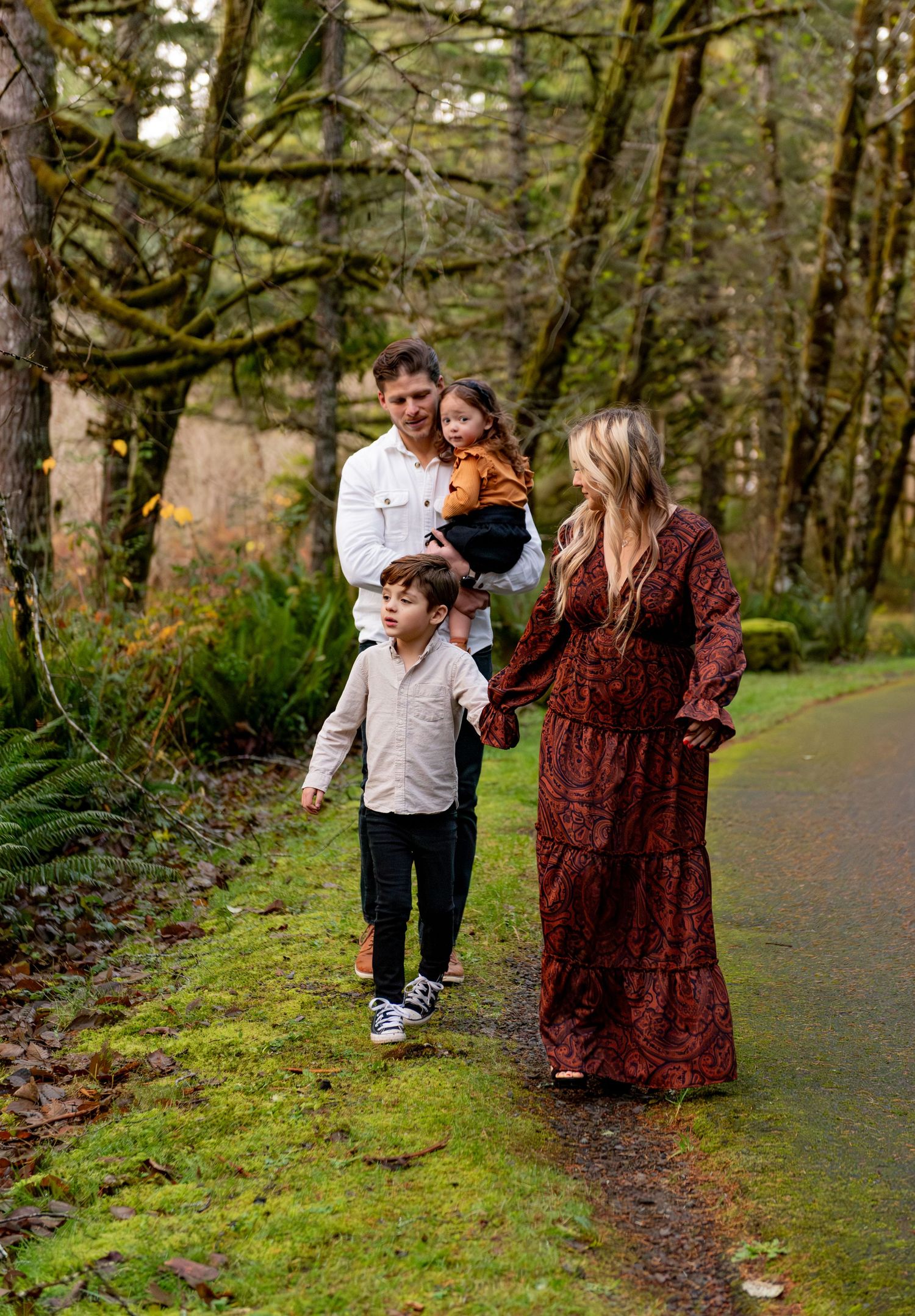 Family enjoying a stroll together on a mossy forest path during an autumn day. Silver Falls State Park, OR