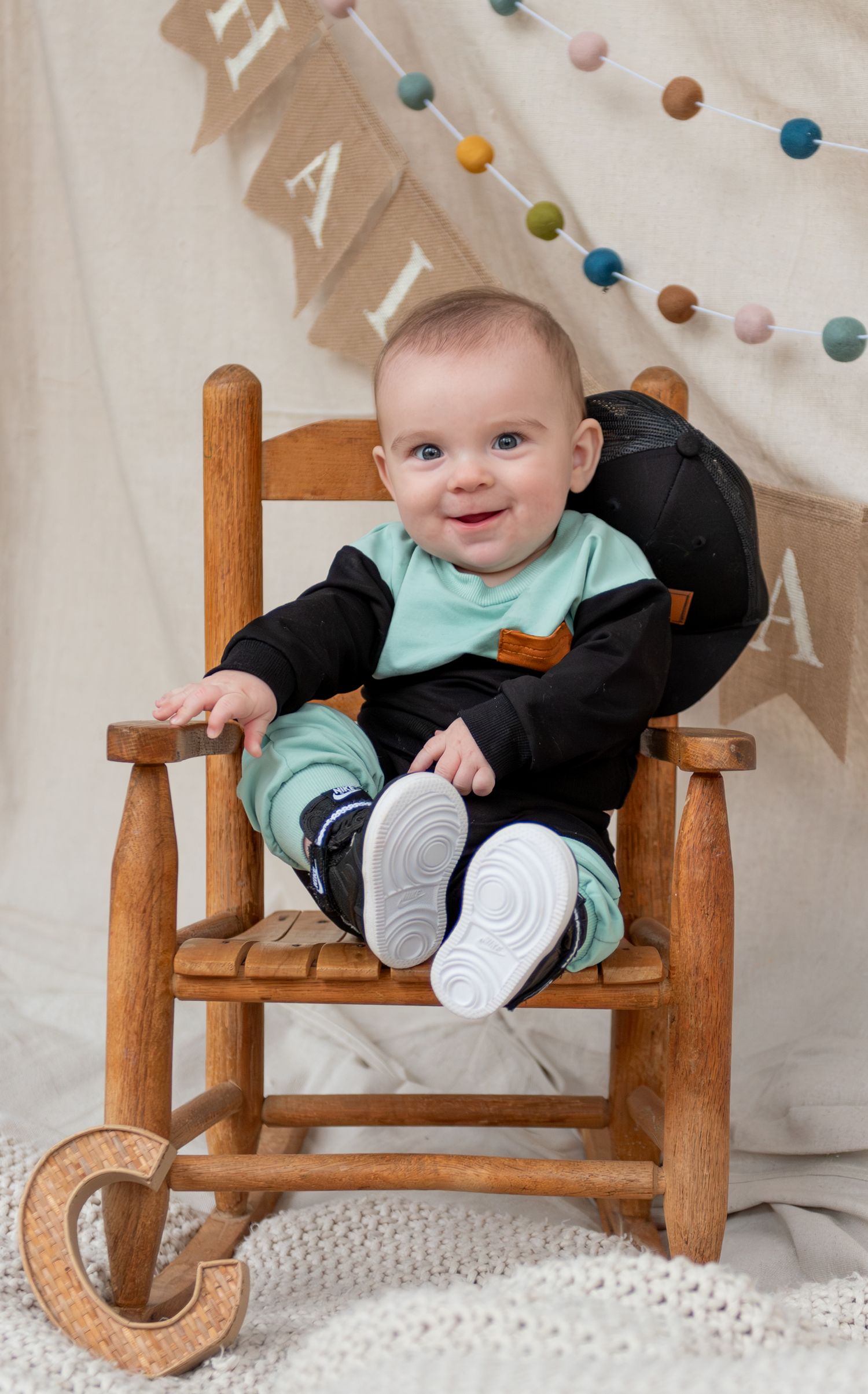 Baby sitting in a chair with a neutral backdrop for a milestone picture.