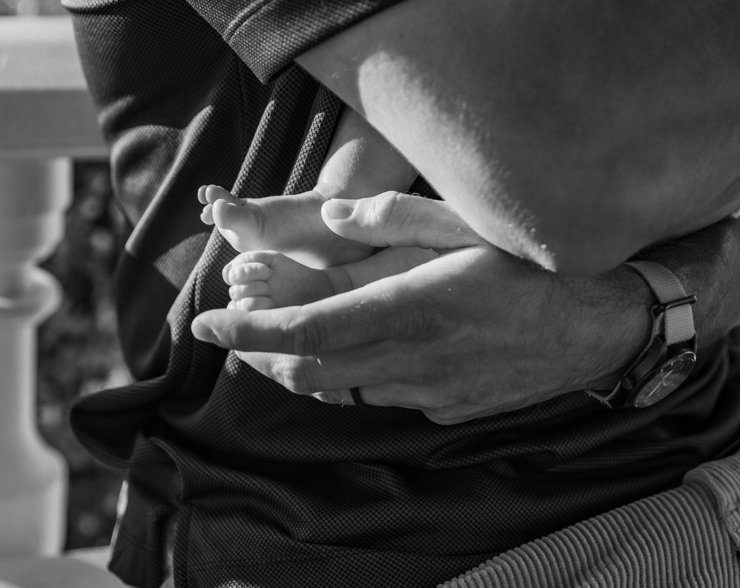 Detail image of Dad's hand holding infant's feet in a black and white photo with natural light, Salem OR.
