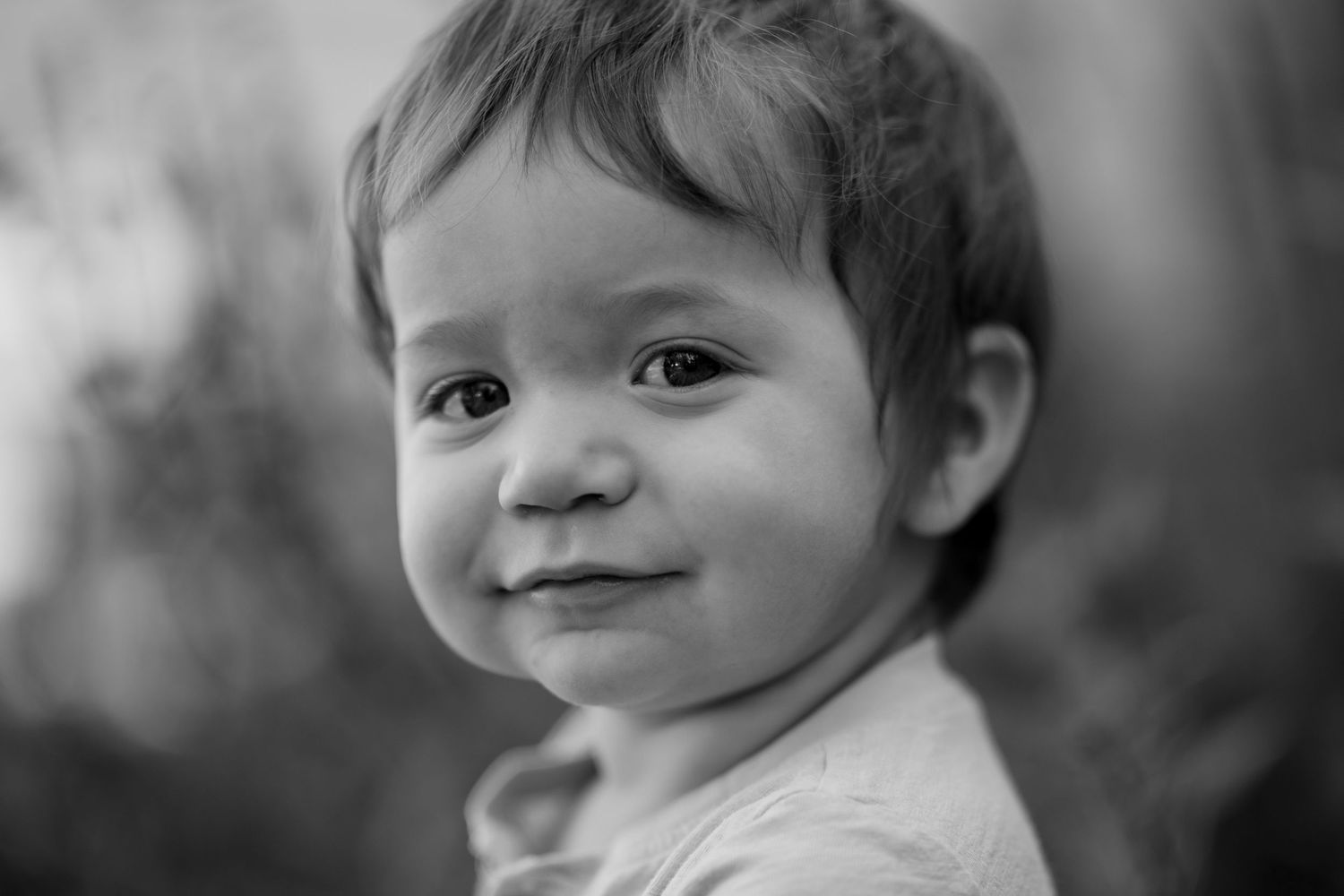 A series of black and white photos showing a child's playful expressions and smiles in a candid portrait sequence.