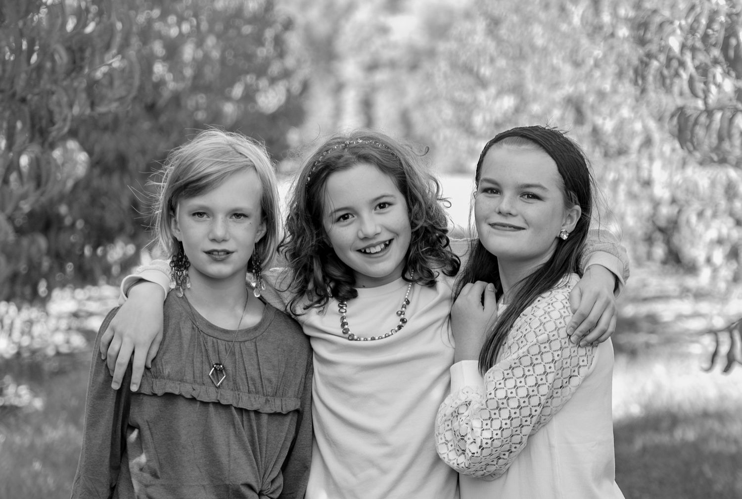 Black and white collage of candid outdoor family moments showing people smiling and embracing in natural settings.