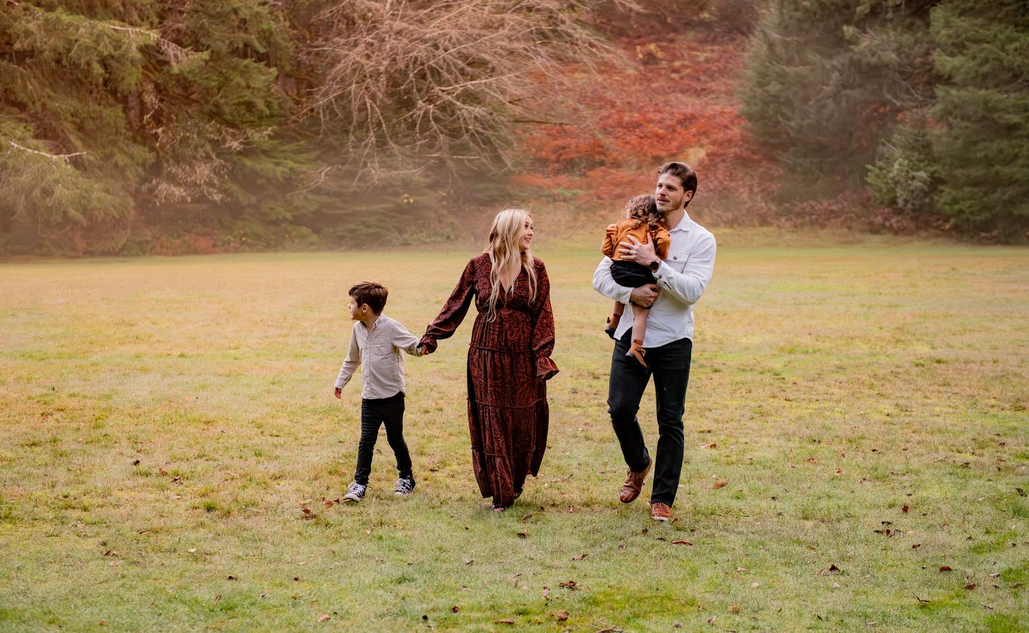 Family enjoying a playful moment together in a sunlit autumn field during golden hour. Silver Falls State Park OR