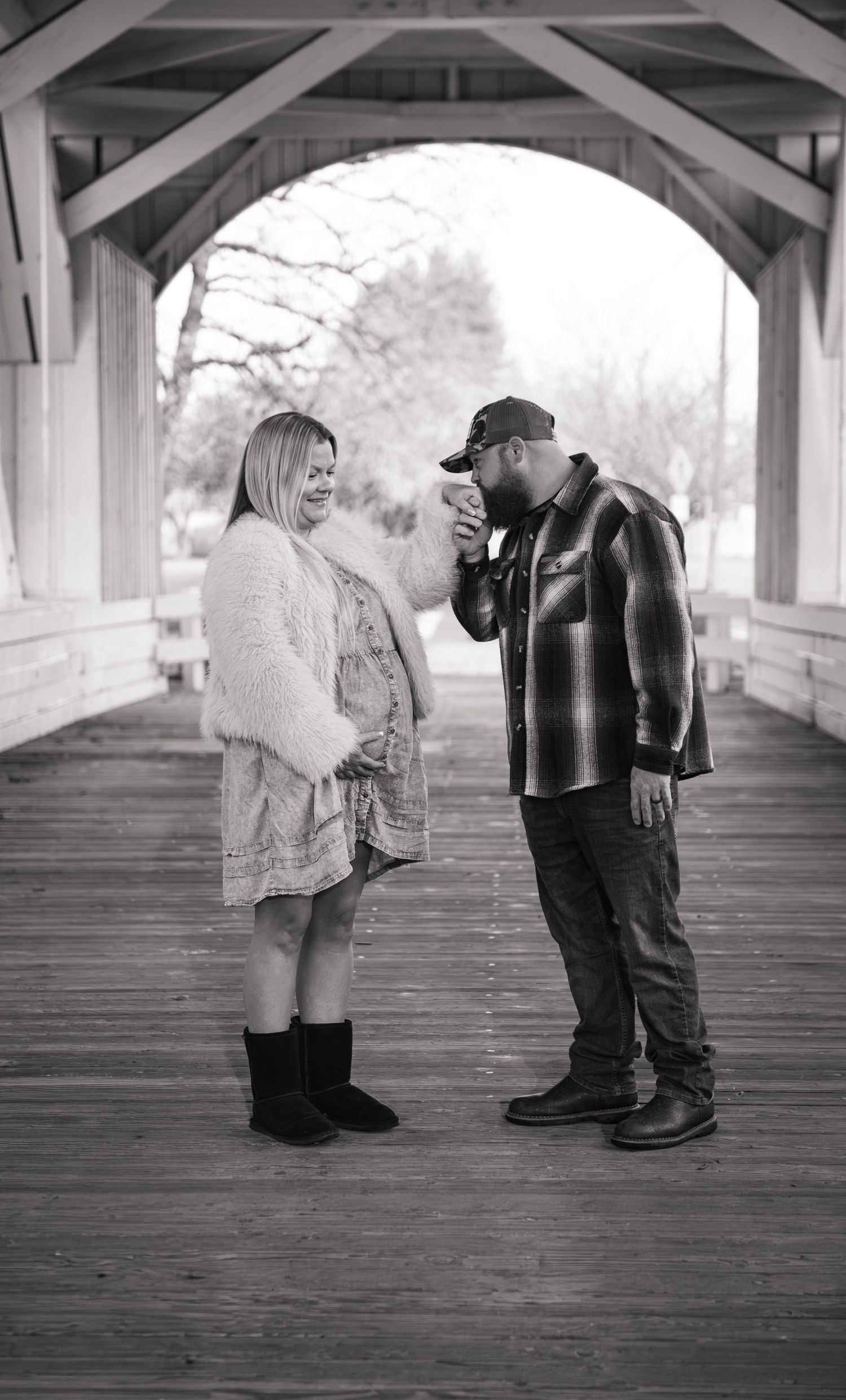 Dad kissing mom's hand while  posed under a covered bridge in Stayton, OR