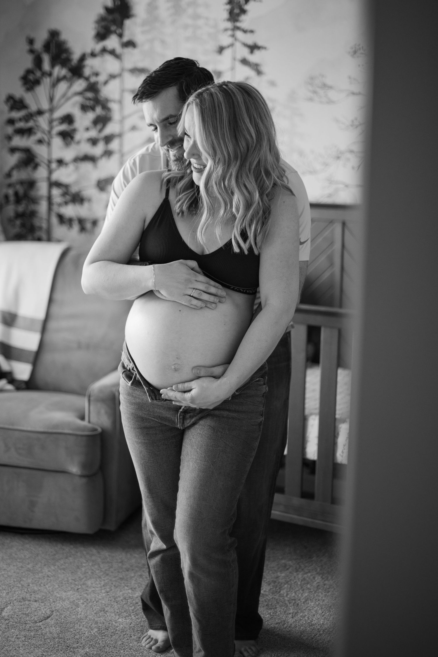 intimate black and white photo showing a couple embracing during a maternity photoshoot in a nursery setting. Located in Salem, OR