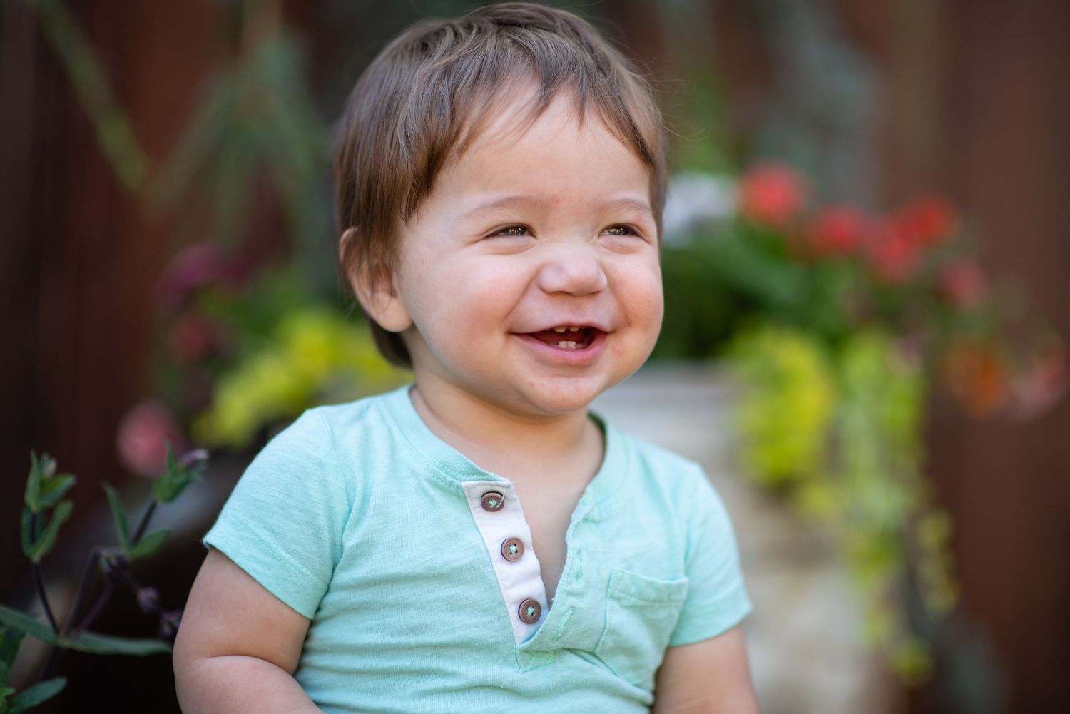 A series of photos showing a baby in a mint green shirt smiling and laughing while sitting outdoors.