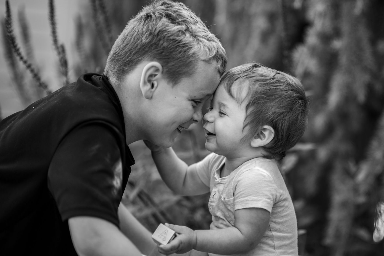 Tender moment between brothers posed forehead to forehead captured in black and white. Location Salem, OR