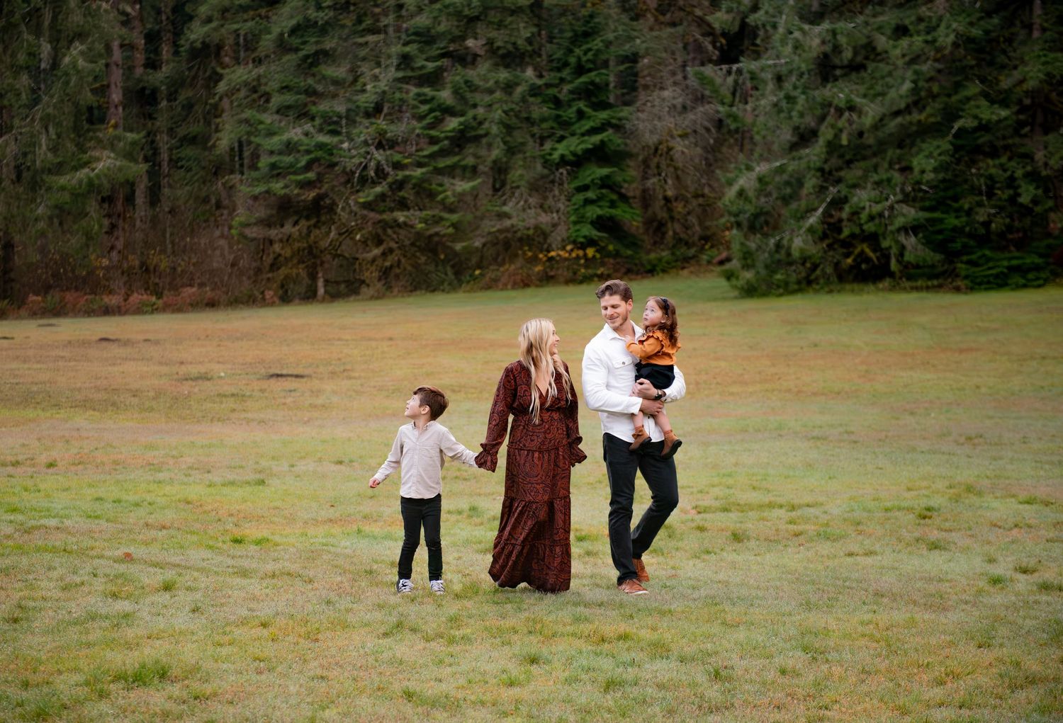 A group of people walking together on a grassy field near a wooded area. Silver Falls State Park OR