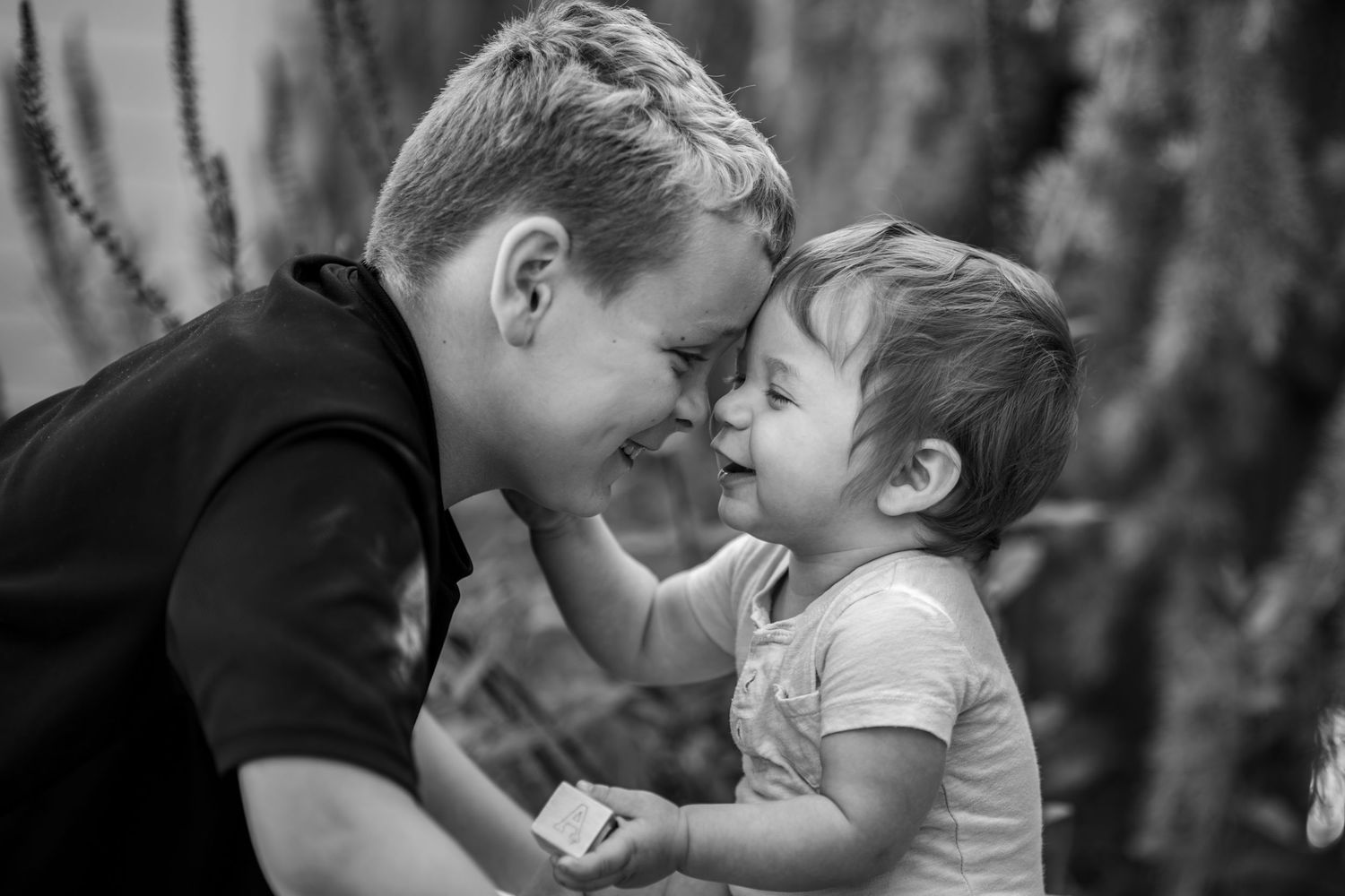 Tender moment between brothers posed forehead to forehead captured in black and white. Location Salem, OR