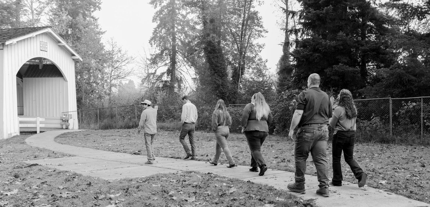 A group of people walking along a path through a wooded area in autumn. located in Stayton, OR