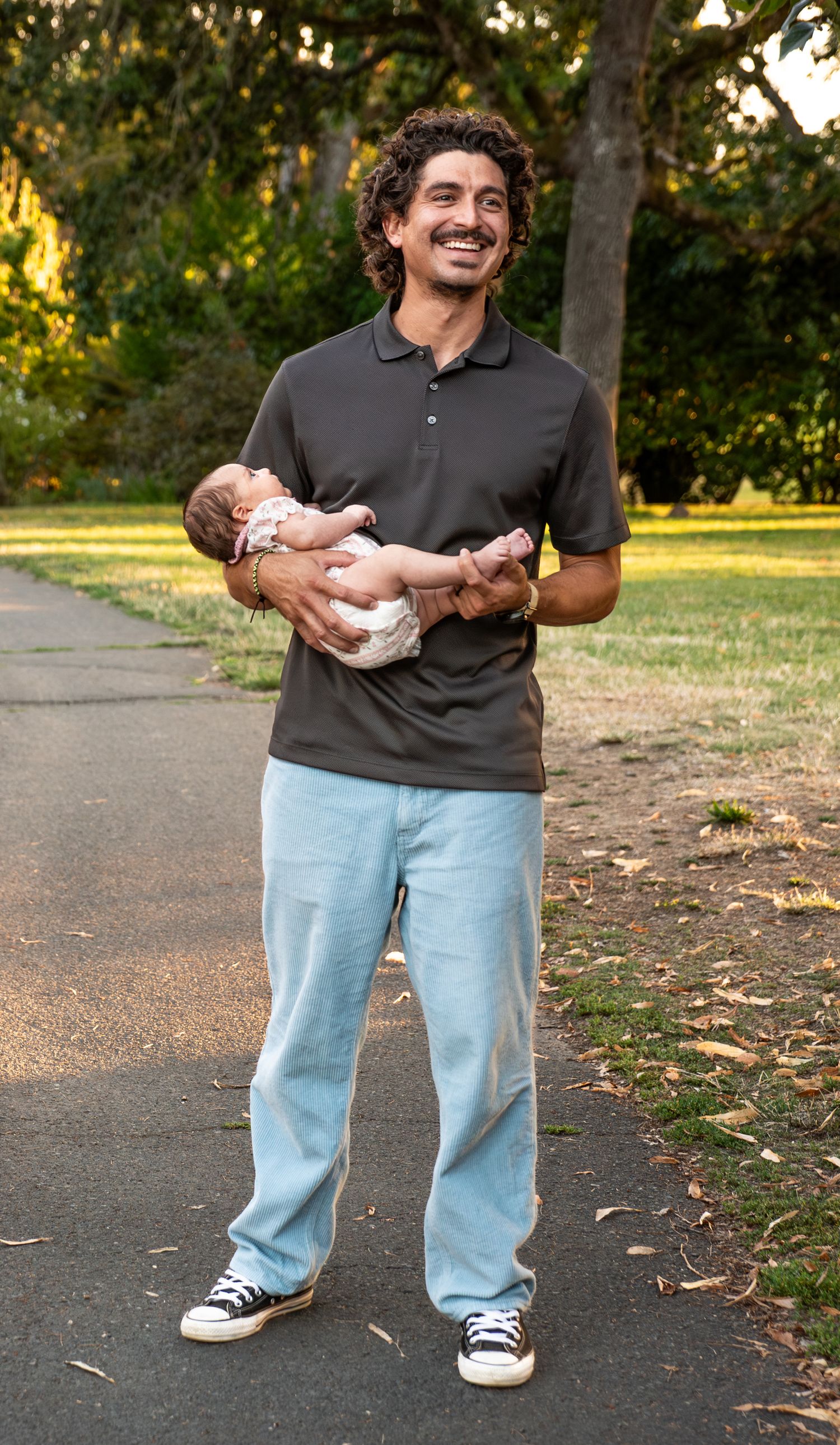 Dad holding infant looing onward towards a friend, true color, true expression, happiness, park, Salem, OR.