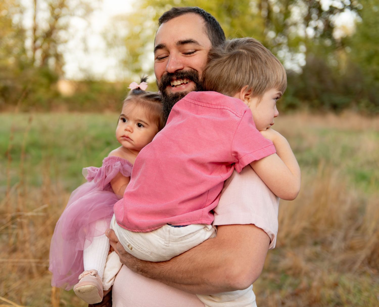 Dad with two children posing in a field with trees in the background in Salem, Or