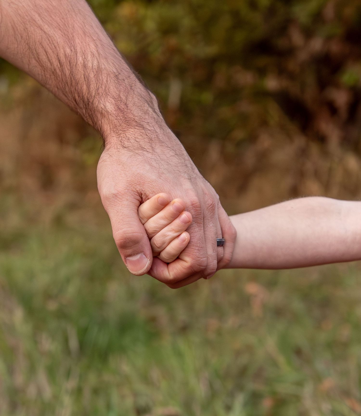detailed image of Young boy holding dads hand located in an open field in Salem, OR
