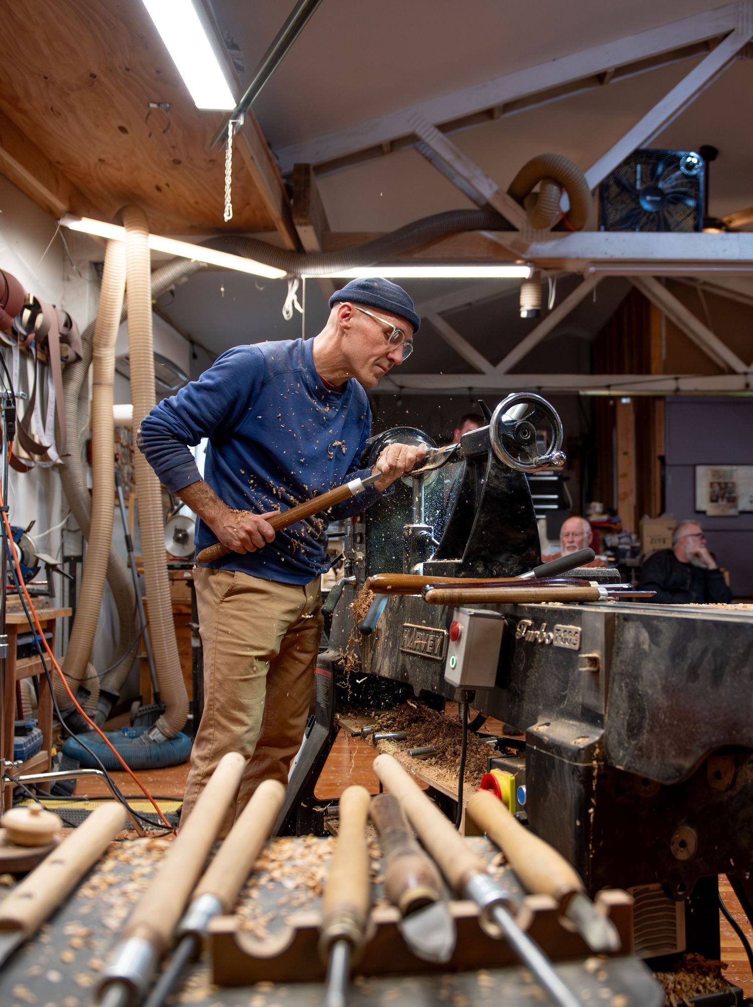 World renowned Wood Tuner turning a small piece of wood on a wood lathe in a wood shop, display of wood working tools. Turner, OR.