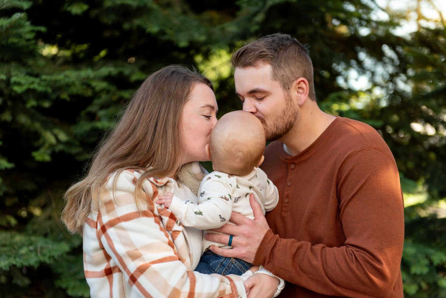 Family shares tender moments together outdoors during golden hour photo session in a lush green setting. Pratum, OR