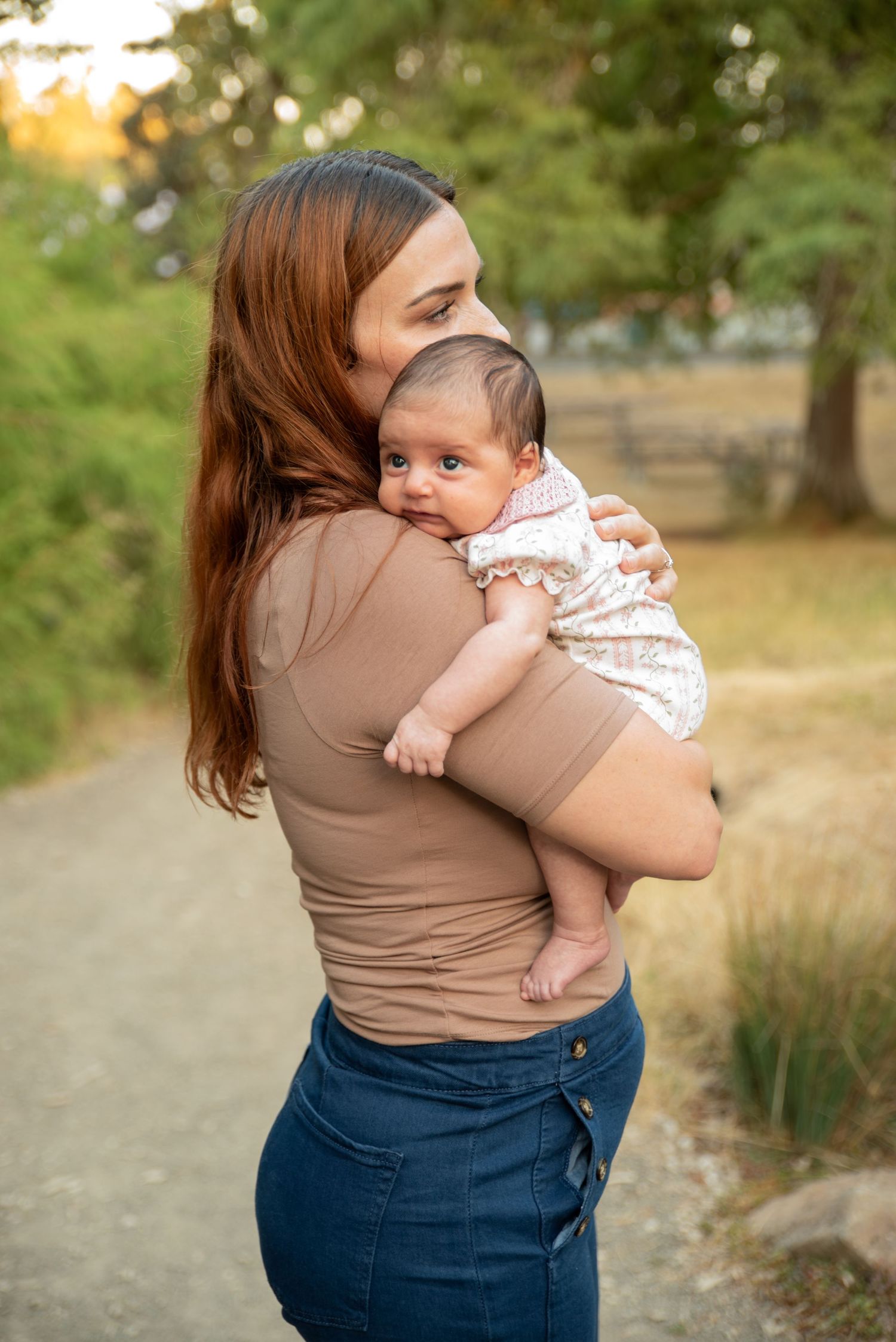 Infant resting on mom's shoulder true colors in a park located in Salem, OR.