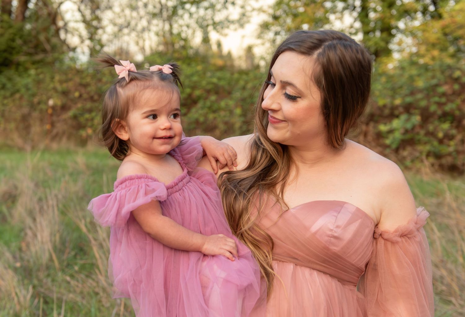 Mother and toddler daughter posing in a field with fall foliage in Salem, OR