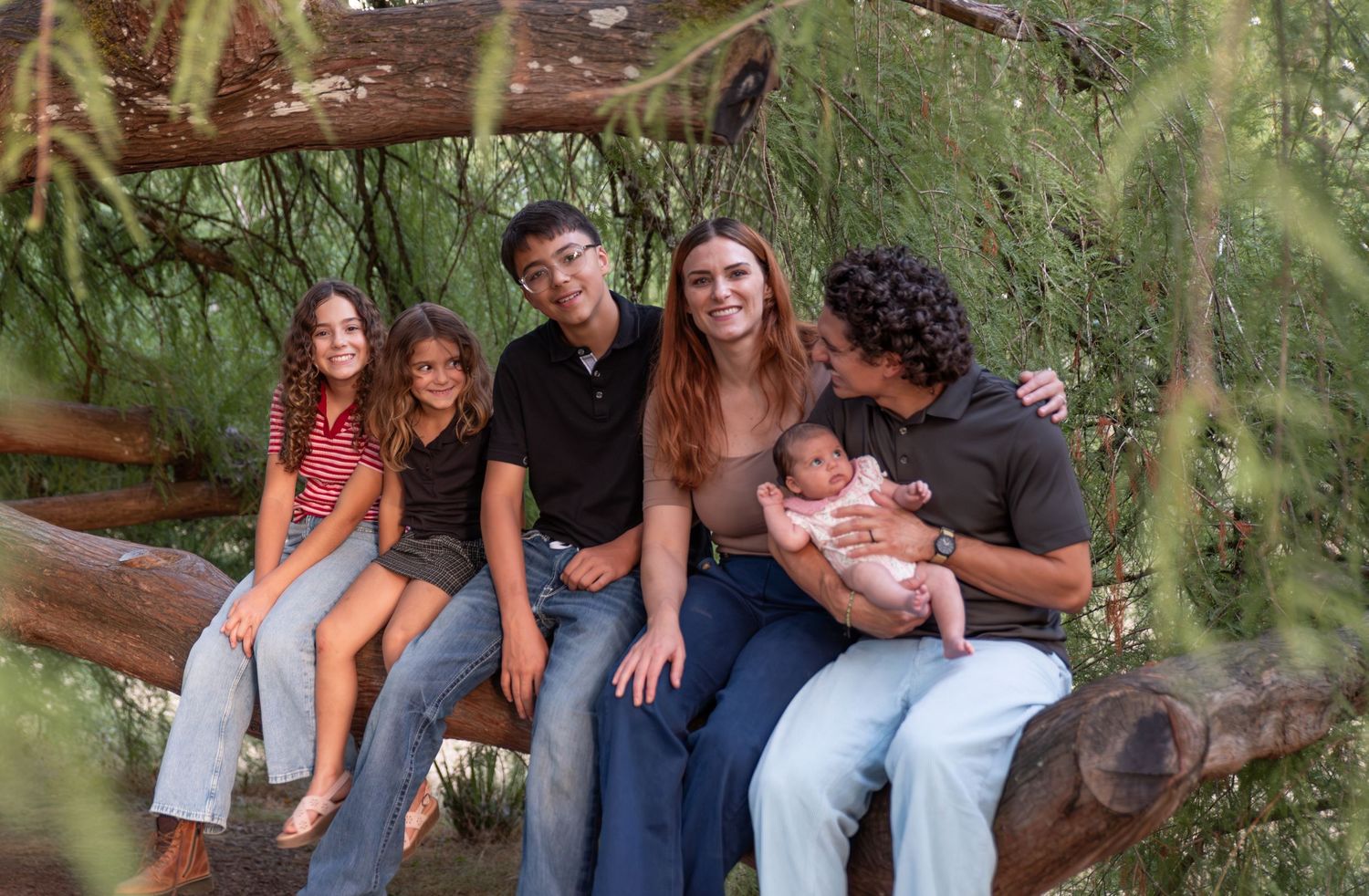Family of six perched on a large willow tree branch, connecting and laughing. ages 14 to newborn. Salem., OR.