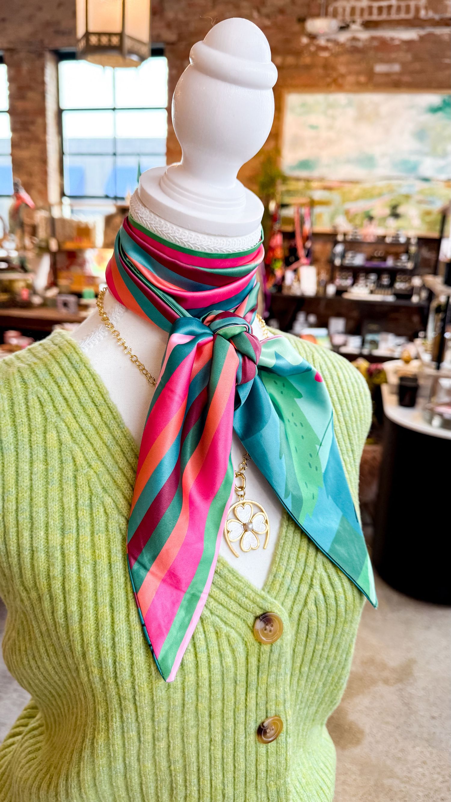 A styled twilly accessory scarf around the neck, styled on a mannequin for an elevated look, showcases the scarf and print for a brand.