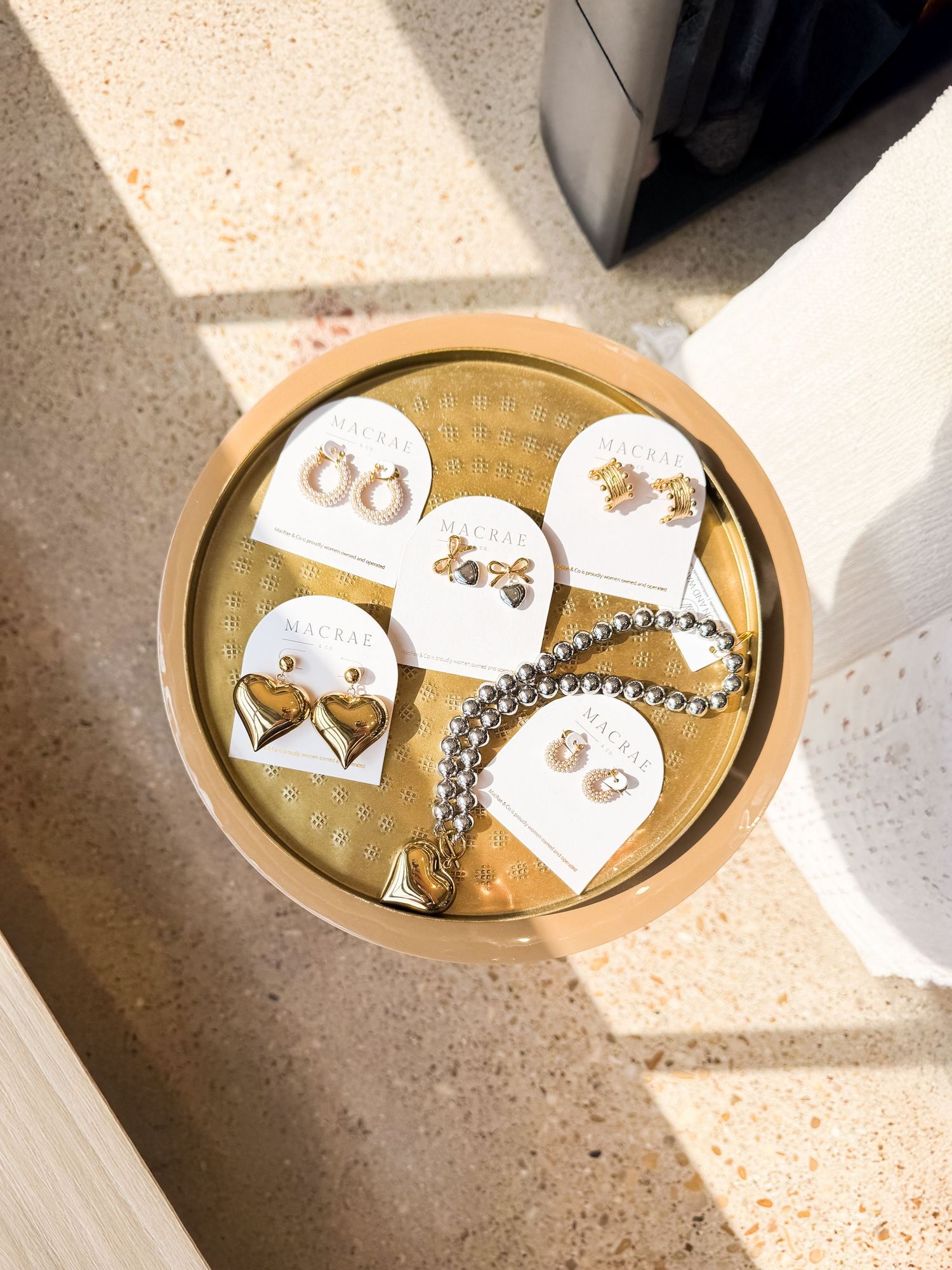 A collection of earrings displayed on a gold table in a local boutique showcases different styles for the brand.
