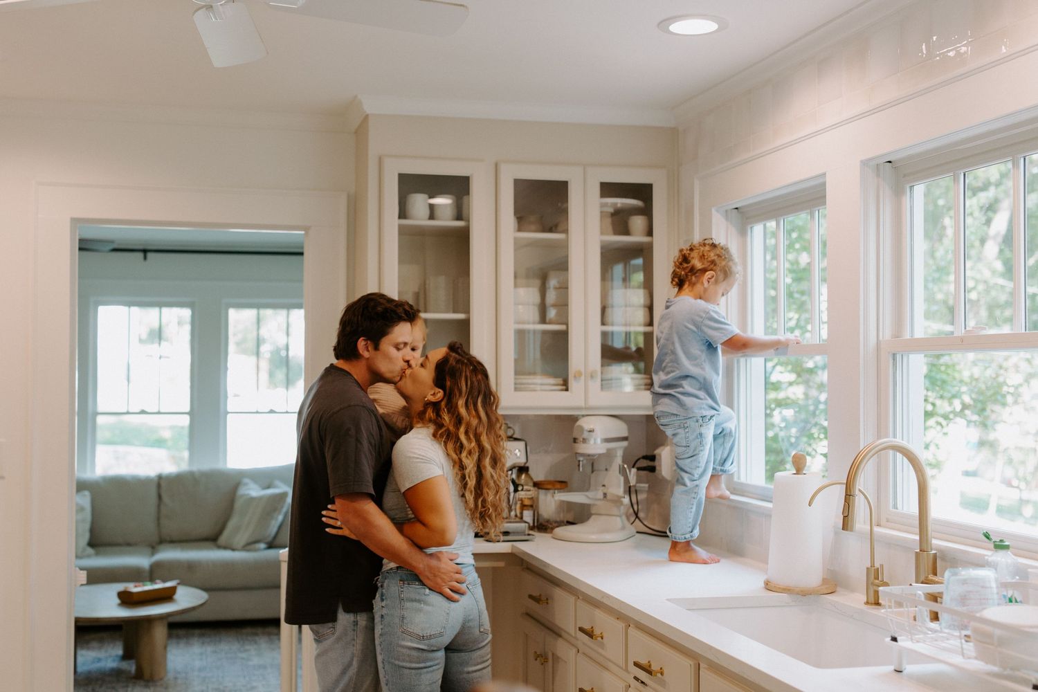 A bright modern kitchen with white cabinets and large windows letting in natural light.