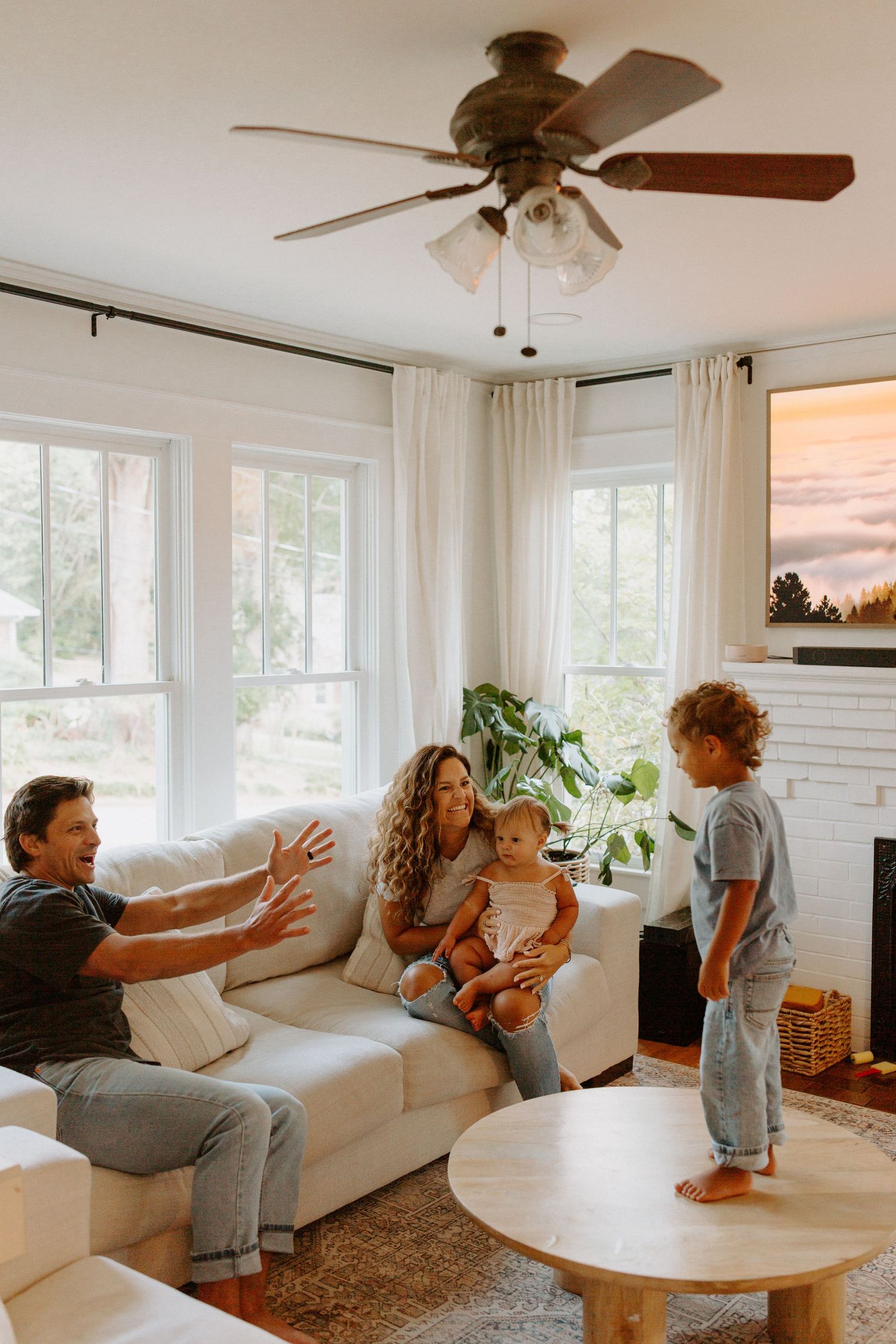 Energetic family play session captured in sequence on white sofa with natural lighting.