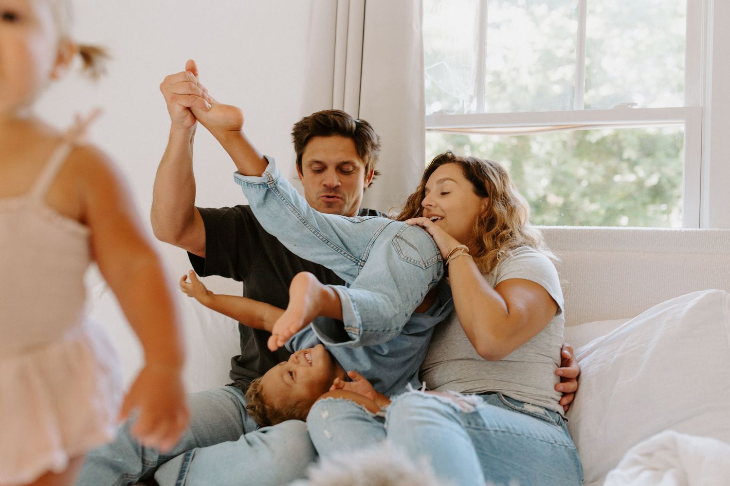 A candid family scene showing playful interaction on a sunny afternoon in the bedroom.