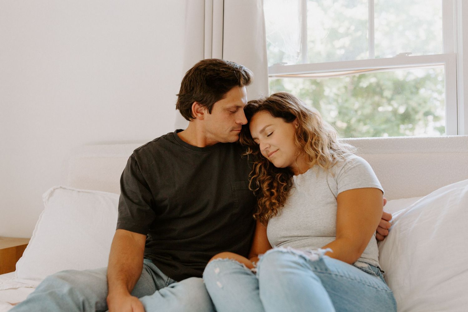 Two people cuddling and showing affection while lounging together on comfortable white furniture.