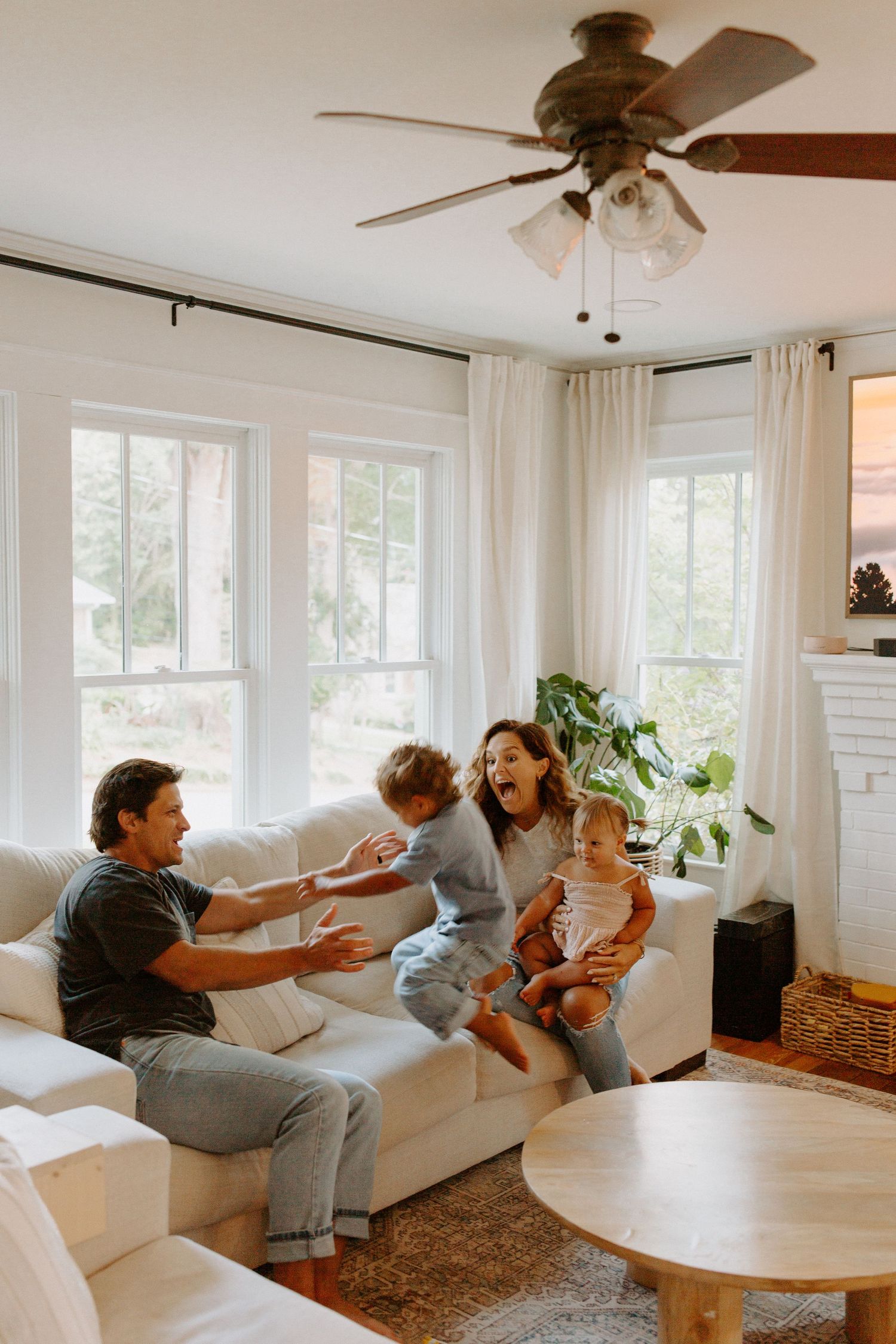 Family enjoying quality time together in a minimalist white living room with ceiling fan.