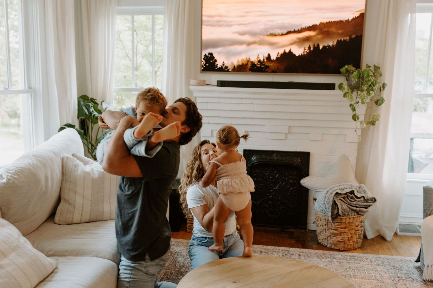 Living room scene with mountain artwork, white sofa, and large windows creating natural ambiance.