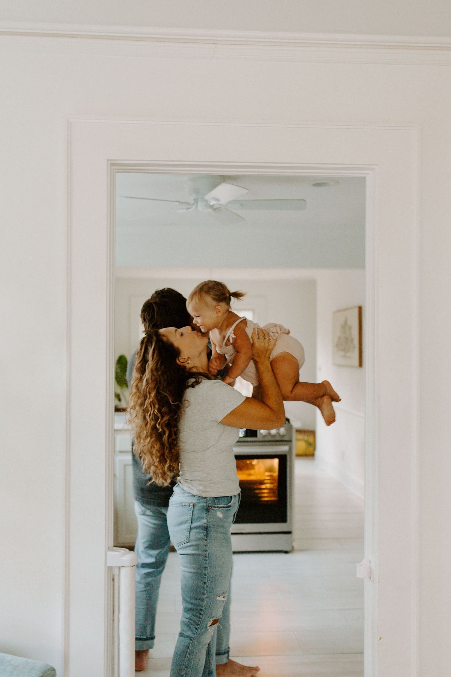 Tender moment in bright kitchen with white appliances and natural light.